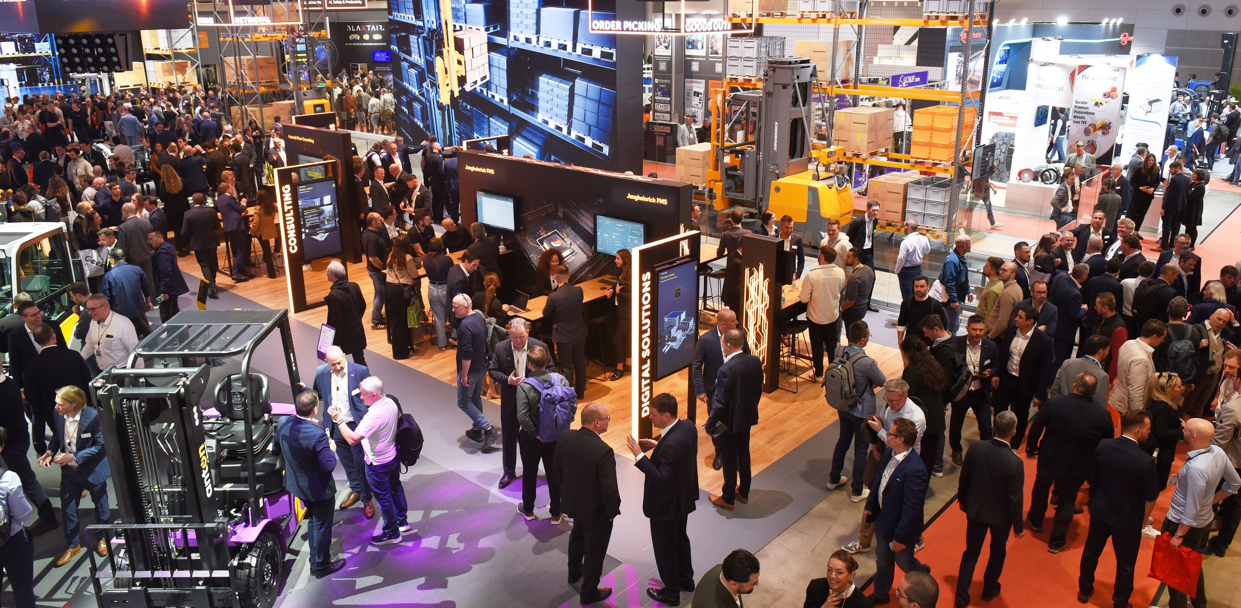 Busy trade fair aisle with visitors between intralogistics and warehouse technology stands